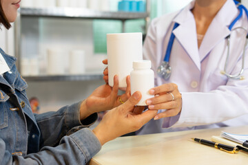 Doctor holding medicine bottle and patient receiving prescription in clinic