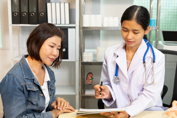 Doctor with stethoscope consulting patient, discussing medical information in clinic room