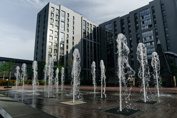 fountain of clean water in courtyard of residential complex, numerous jets of water, multi-storey...