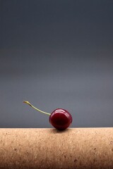 Concept of individuality and focus: a single red cherry on a dark background.