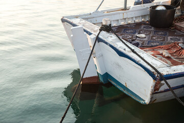 Stern of a vintage fishing boat docked in calm harbor waters, showing rustic charm