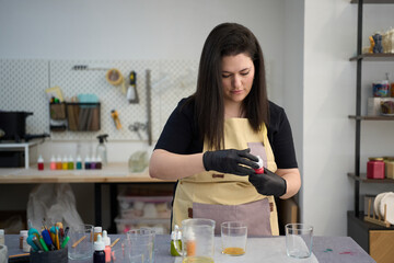 Candle maker adding dye to wax in workshop