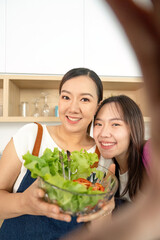 Healthy Cooking and Bonding. Two women preparing fresh salad together in a modern kitchen.