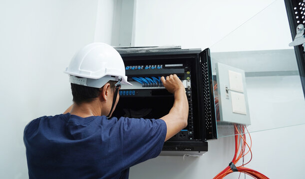 A maintenance technician works in a server room with a fiber optic hub