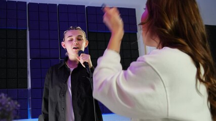 Student sings during vocal repetition under teacher guidance. Women work in tandem in music studio reverberating with rich sounds slow motion