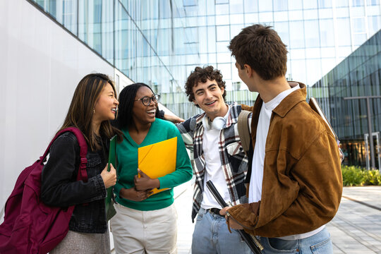 Cheerful university students talking and laughing together outdoors