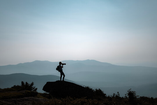 Woman stands on rock taking photo, Appalachain Trail, Maine