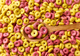 wooden spoon of corn rings and strawberry rings above tasty corn rings as background. Top view....