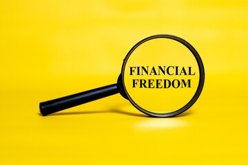 FINANCIAL FREEDOM concept zoomed through a magnifying glass isolated on a yellow background.