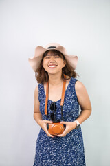Happy beautiful young asian woman wearing blue summer dress and beach straw hat, isolated over white background. Concept for travel, solo traveling and long weekend