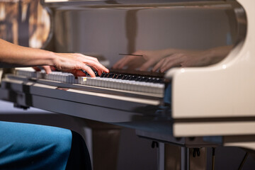 Female hands and white pianoforte keys