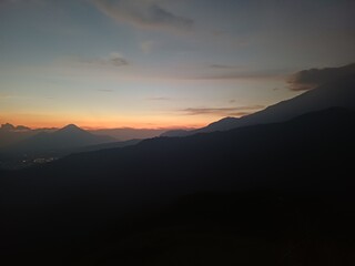Panoramic view of silhouetted mountains against a twilight sky, showcasing a gradient of warm...