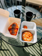 Morning pastries and coffee on a balcony table in the sunlight