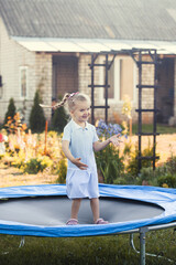 Little girl jumping on a trampoline on a summer day.