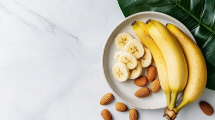 White plate with a bunch of bananas and sliced bananas on it. the bananas are yellow with brown spots and appear to be ripe and ready to eat. there are also a few almonds scattered around the plate.