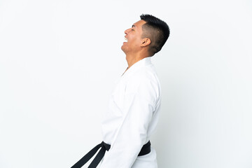 Young Ecuadorian man doing karate isolated on white background laughing in lateral position