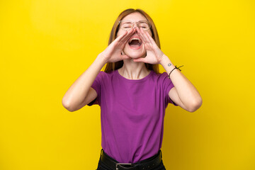 Young English woman isolated on yellow background shouting and announcing something