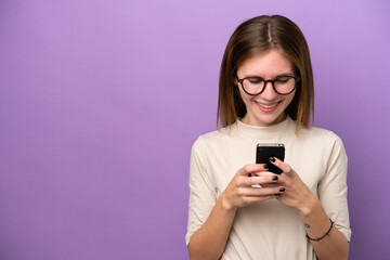 Young English woman isolated on purple background sending a message with the mobile
