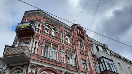 Kyiv, Ukraine, 06.26.2025, beautiful old pink house with Ukrainian flag on balcony