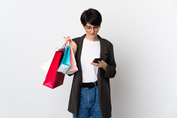 Woman with short hair isolated on white background holding shopping bags and writing a message with...
