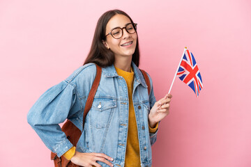 Young French girl holding an United Kingdom flag isolated on pink background posing with arms at...