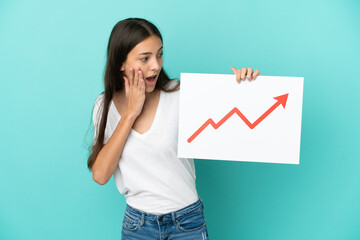 Young French woman isolated on blue background holding a sign with a growing statistics arrow...