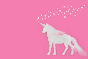 Fantasy unicorn Christmas tree frosted bauble decoration with glitter stars on pink background. Magical symbol for the festive holiday season. Greeting card, gift tag, invitation.