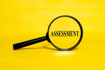 ASSESSMENT concept zoomed through a magnifying glass isolated on a yellow background. 