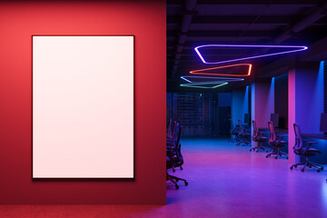 Blank vertical poster template on red wall in modern neon-lit office interior with computer desks...