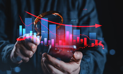 Obraz na płótnie Canvas Businessman analyzing financial data with magnifying glass and smartphone, highlighting market trends and economic downturn concept.
