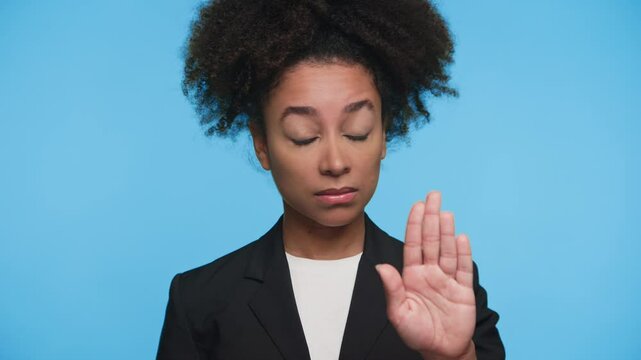 Serious woman making stop gesture with hand on blue