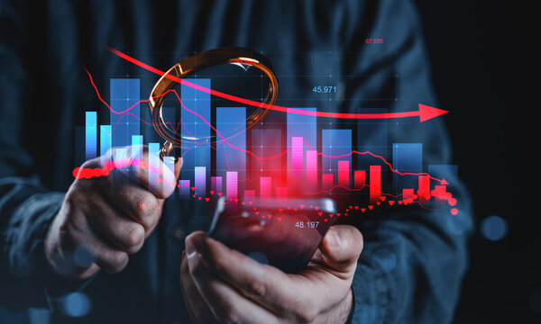 Businessman analyzing financial data with magnifying glass and smartphone, highlighting market trends and economic downturn concept.