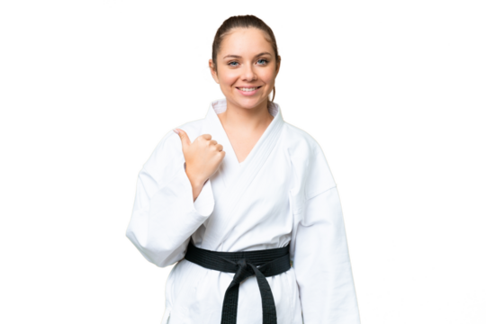 Young blonde woman doing karate over isolated chroma key background pointing to the side to present a product