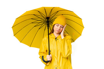Young blonde woman with rainproof coat and umbrella over isolated chroma key background with...