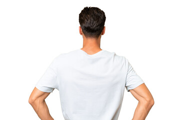 Young caucasian handsome man over isolated background in back position