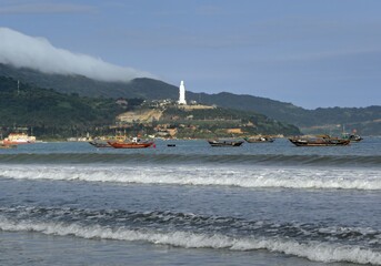  looking out across the beach and waves in da nang in central vietnam at the lady buddha statue at linh ung pagoda on son tra peninsula on da nang bay    