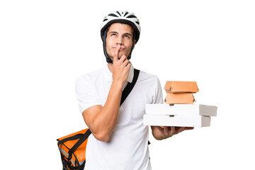 Young caucasian man with thermal backpack over isolated background having doubts while looking up