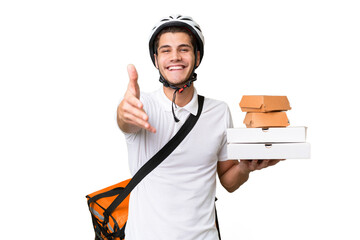 Young caucasian man with thermal backpack over isolated background shaking hands for closing a good...