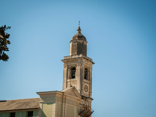 Photo taken in a square in Loano, province of Savona (Liguria, Italy). The clear sky highlights the architectural details of the traditional church bell tower.