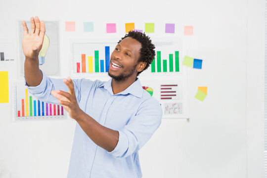 African American man in blue shirt standing in meeting room presenting bar charts and sticky notes - Powered by Adobe
