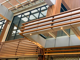 Modern architectural interior with wood and metal panel design, featuring geometric lines, glass, and lighting. Contemporary structure with clean aesthetic and industrial style.