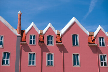 Colorful Pink Building with Symmetrical Windows and Red Tiled Roof under Blue Sky. Cascais Portugal