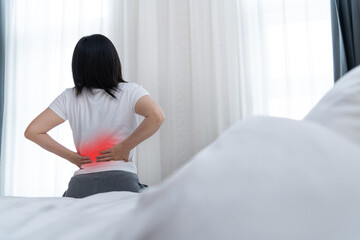 Women with lower back pain sitting by the bed