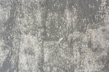 Close-up of a textured, cracked gray and white painted wall surface showing peeling layers and aged...