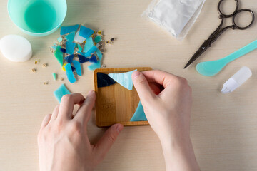 Faux stained glass fragments positioned in silicone mold to make handmade mosaic-style coaster with...