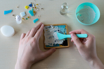 Mixing gypsum compound with plastic spoon for casting mosaic-style drink coaster in silicone mold...