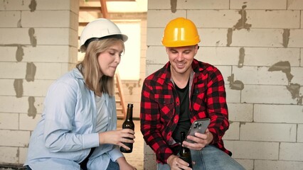 Construction workers using cellphone over beer during work break