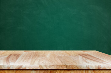 Empty wooden table with copy space on school table with green writing board in background