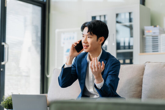 Asian Businessman sitting in office using a cellphone and laptop.