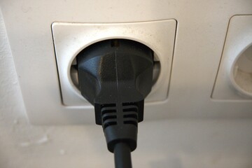 Black plug in the white socket close up